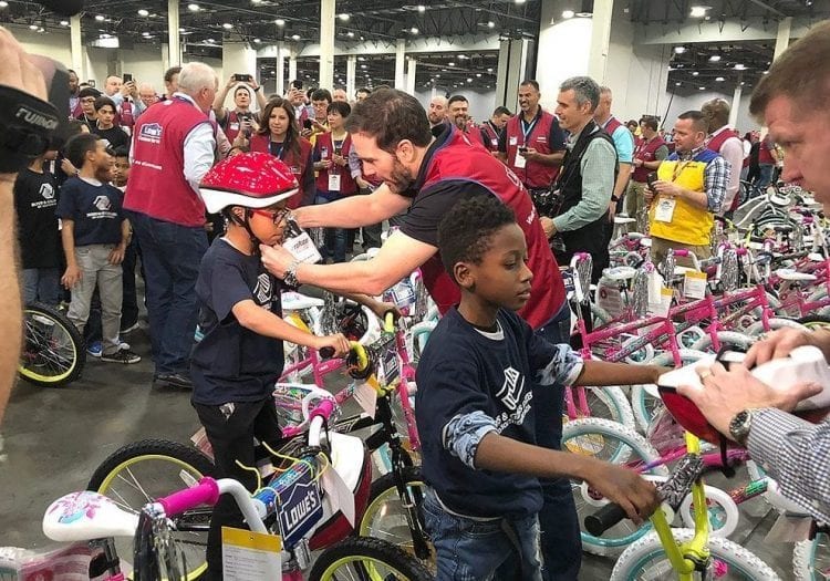 A group of people standing in front of a group of children.