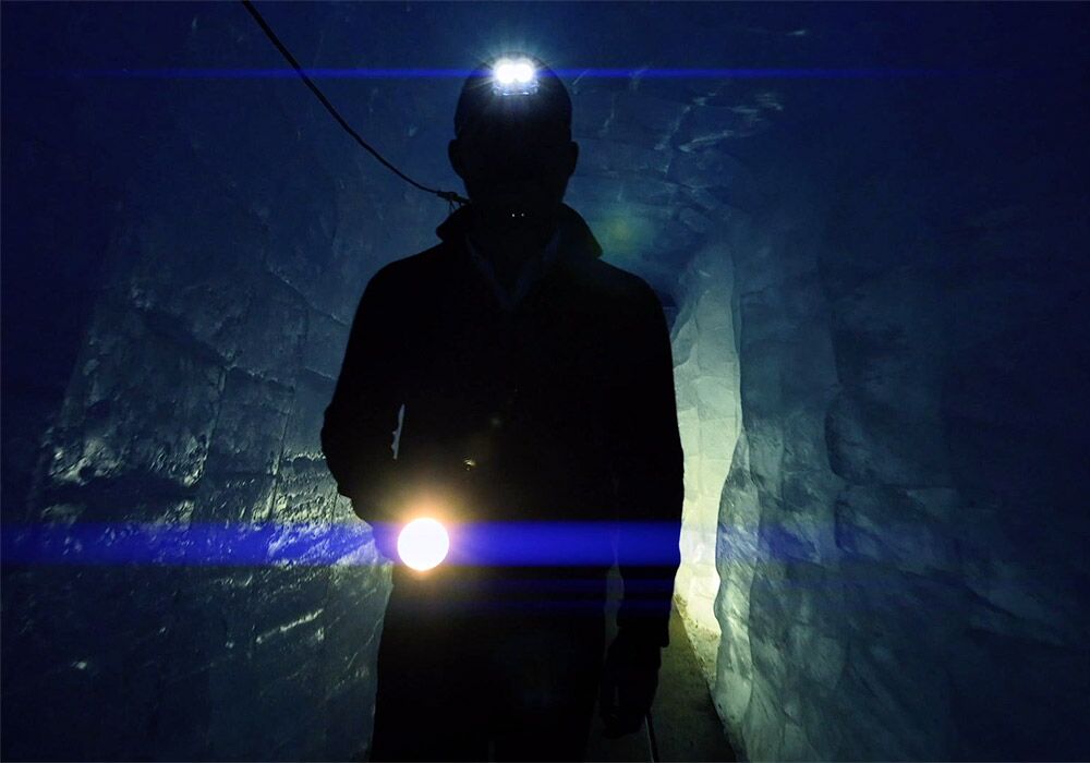 A man holding a flashlight in a dark tunnel.