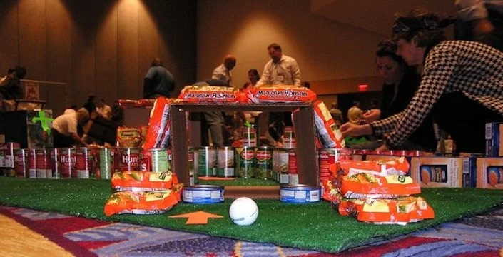 A group of people standing around a table with cans on it.
