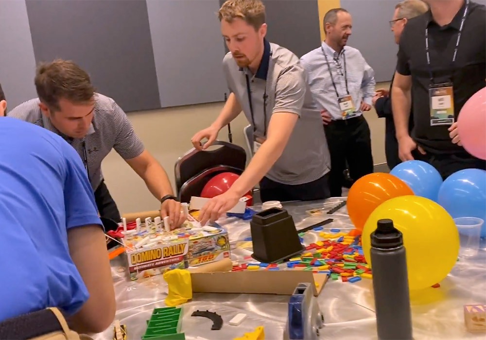 A group of people standing around a table with balloons and legos.
