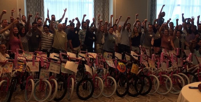 A group of people posing with bicycles in front of them.