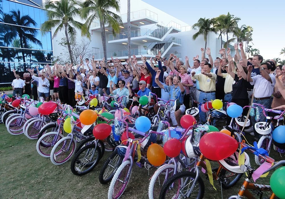 A group of people standing in front of a group of bicycles.