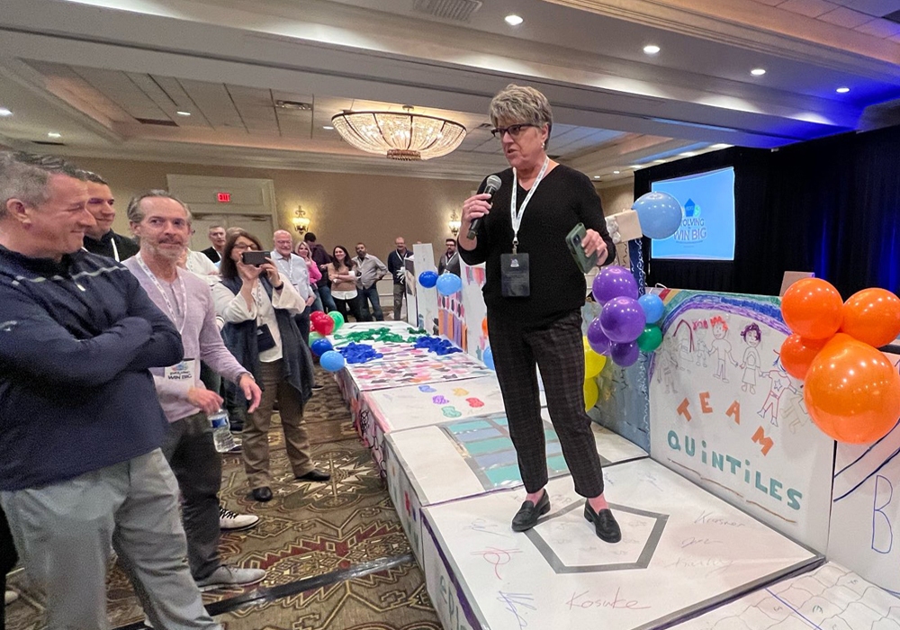 A woman standing on stage in front of a crowd of people.