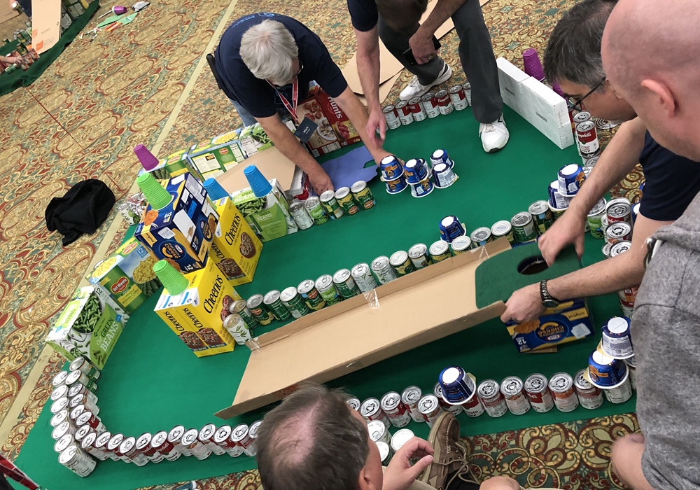 A group of people working on a cardboard race track.