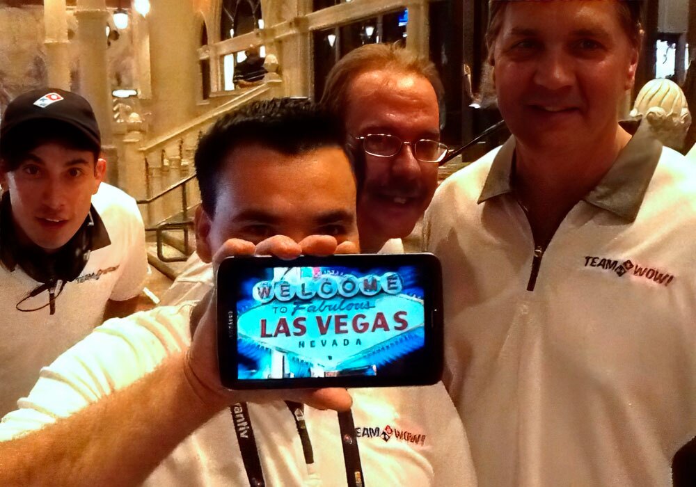 A group of men are taking a picture with a tablet.