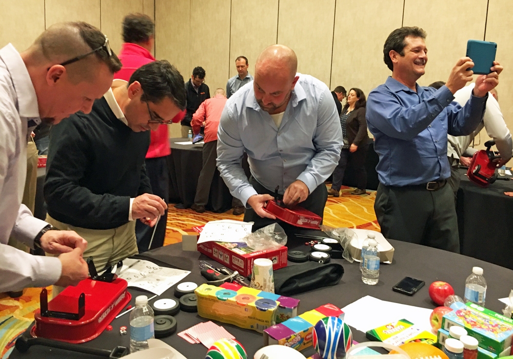 A group of men are making crafts for a Toy Donation drive at a table.