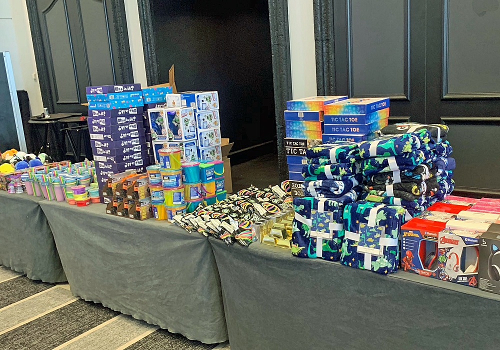 A table full of toiletries, along with a toy donation box, on a table in a room.