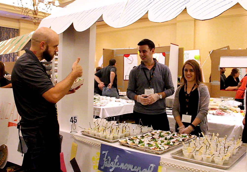 A group of people standing in front of a table with food.