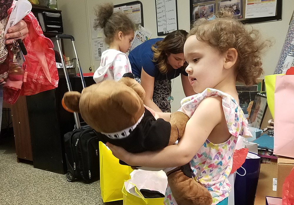 A young girl holding a teddy bear.