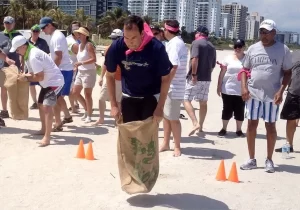 A group of people standing on an outdoors beach with orange cones.