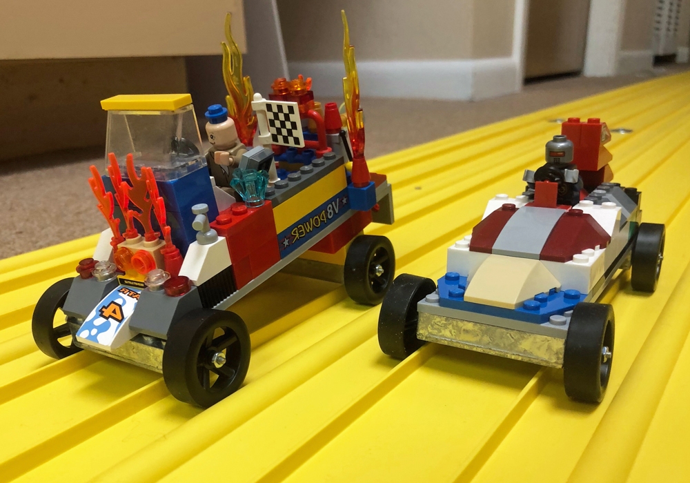 Two lego cars on a yellow surface.