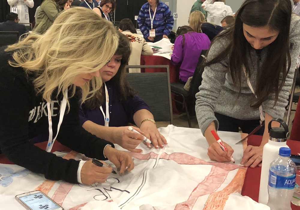 A group of women working on a t - shirt.