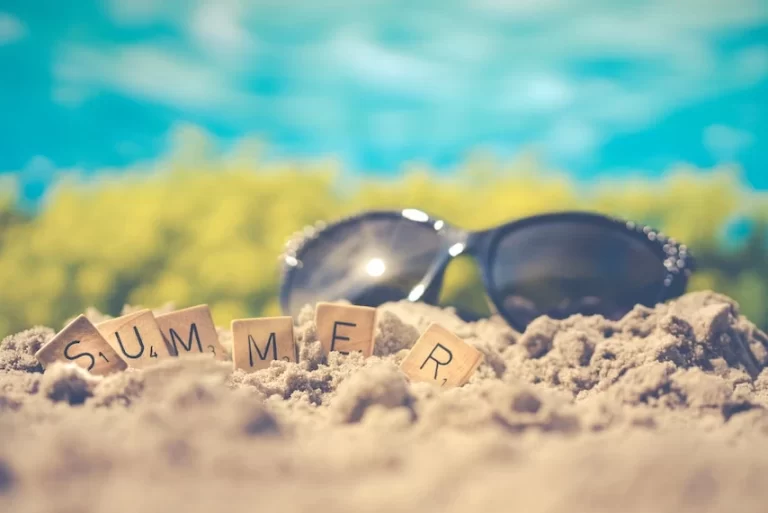 Sunglasses and the word summer spelled out in the sand.