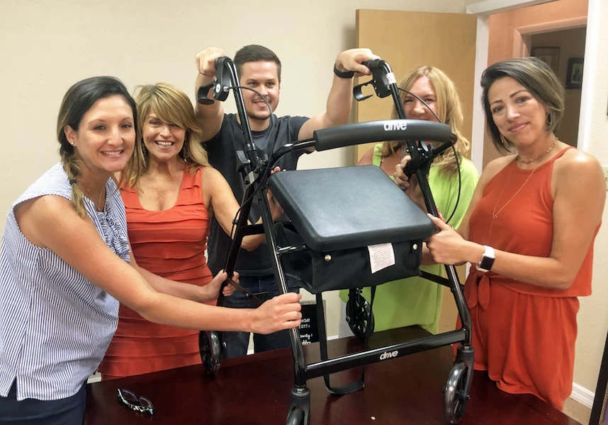 A group of people posing with a walker.