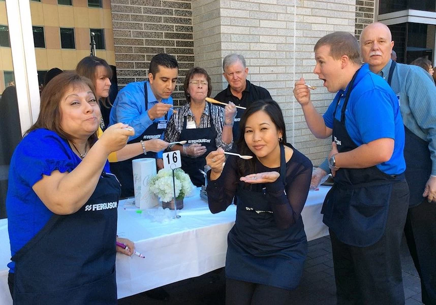 A group of people standing around a table eating food.