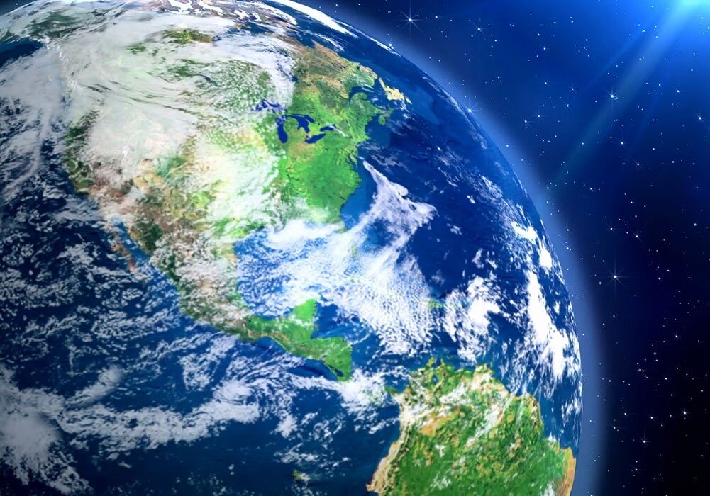 The earth is seen from space with the sun shining on it.