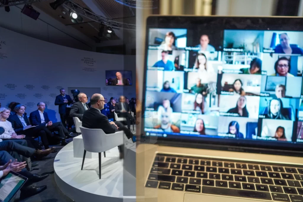 A laptop screen displaying a hybrid event with a group of people on a conference call.