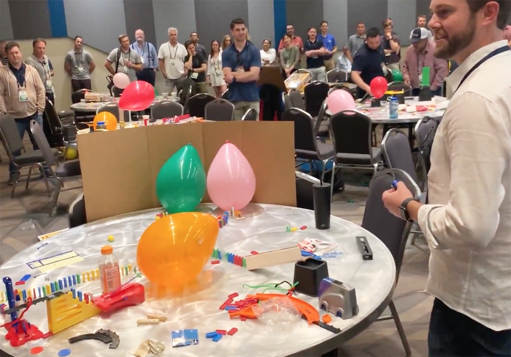 A group of people standing around a table with balloons.