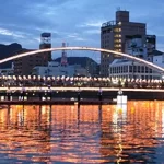 A bridge over a river with lit up lanterns.