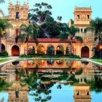 A corporate events venue with an ornate building, surrounded by a serene pond and shaded by tall palm trees in San Diego.
