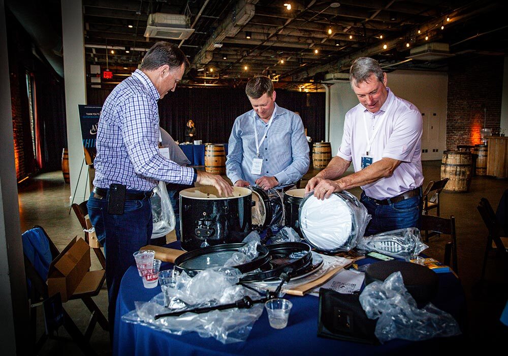 Three men standing around a table with barrels.
