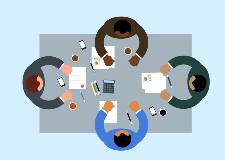 Four people sit around a table with documents, charts, coffee cups, and a calculator—engaged in workplace rituals of collaboration and discussion.