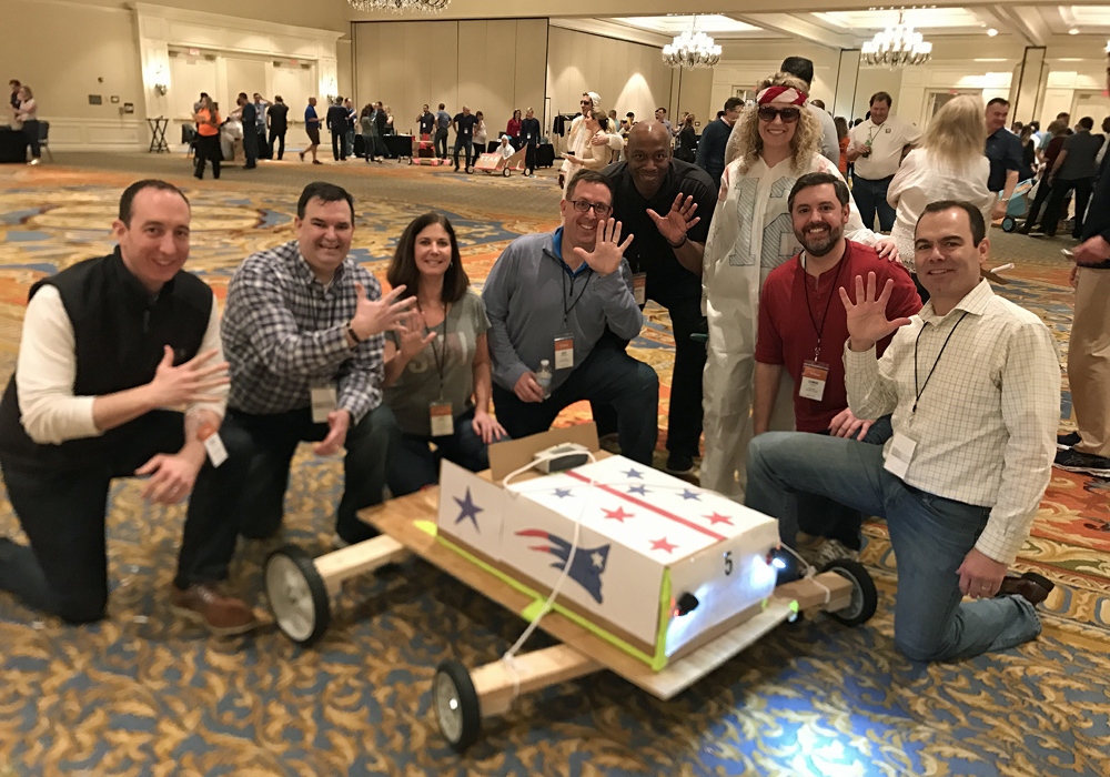 A group of people posing with a cardboard car.