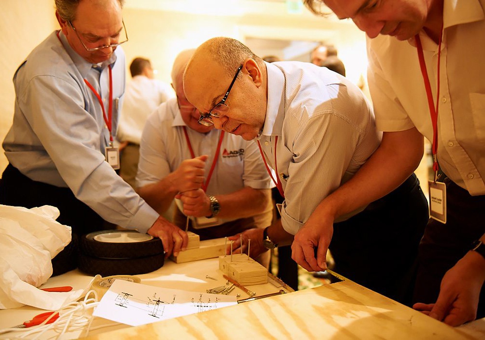 A group of men working on a piece of wood.