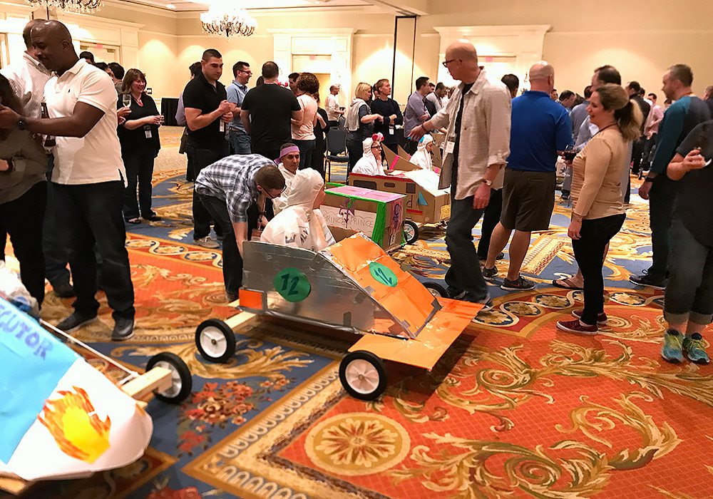 A group of people standing around a room full of cars.