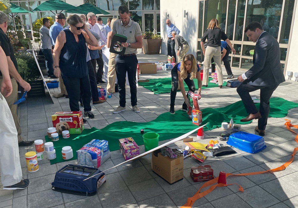 A group of people standing around a table with a lot of items on it.