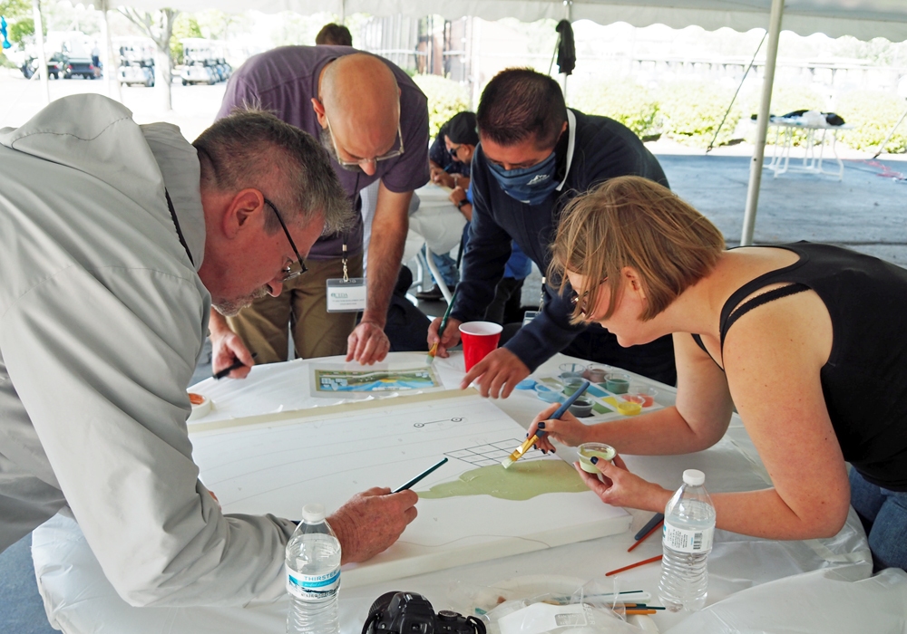 A group of people sitting around a table painting.