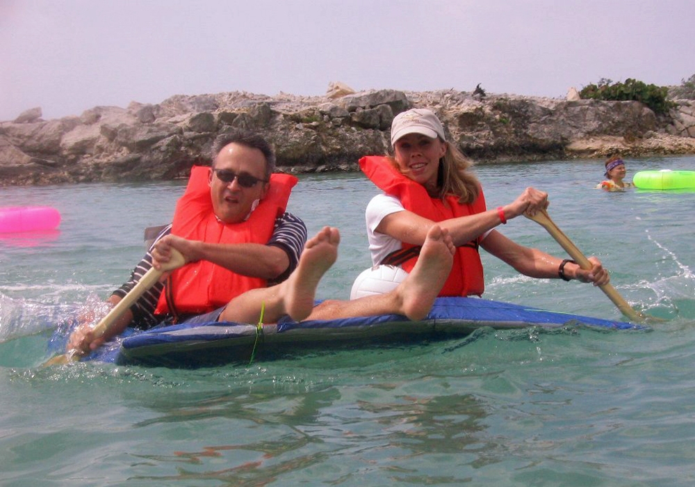 A man and woman riding a raft in the ocean.
