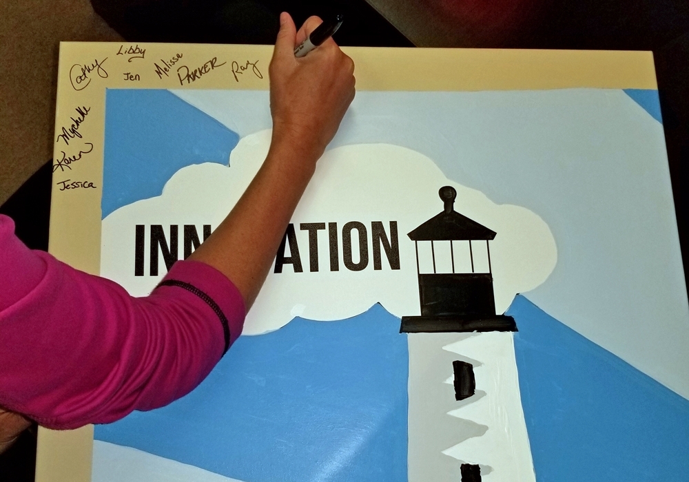 A woman writing on a lighthouse sign.