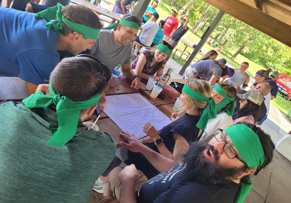 A group of people sitting around a table with green bandanas.