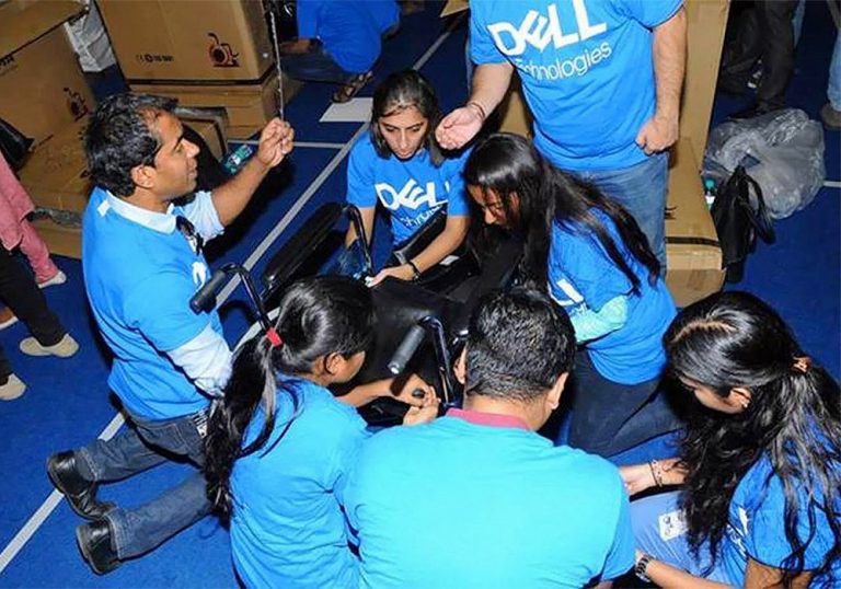 A group of people in blue t - shirts sitting on the floor.