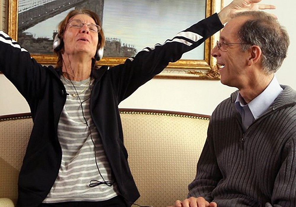 A man and woman sitting on a couch with their arms outstretched.