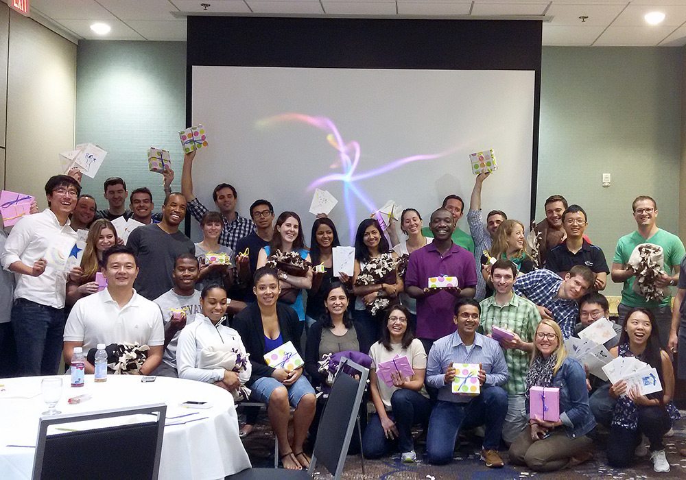 A group of people posing for a picture in front of a projector.
