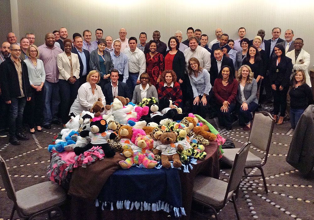 A group of people posing for a photo with stuffed animals.