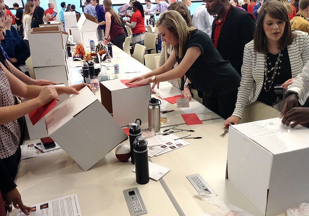 A group of people standing around a table with boxes.
