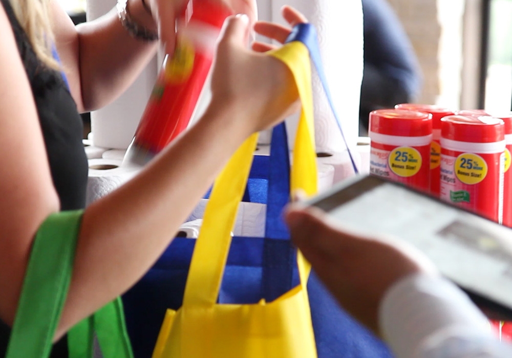 A woman is holding a bag and a tablet.