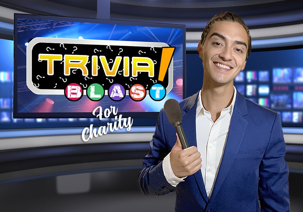 A smiling man in a blue suit holds a microphone in front of a screen displaying "Trivia Blast for Charity" in a studio set.
