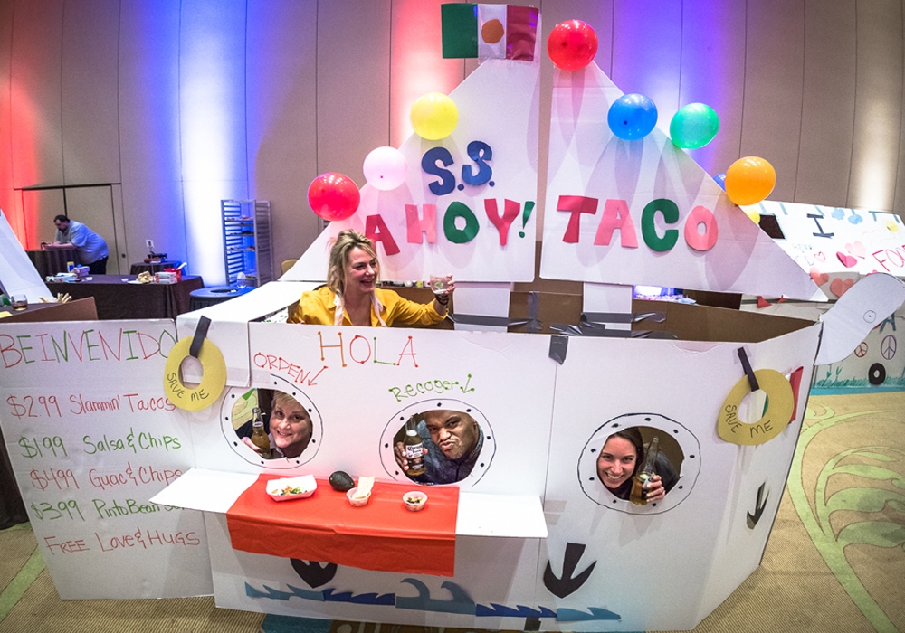 A group of people standing in front of a cardboard ship.