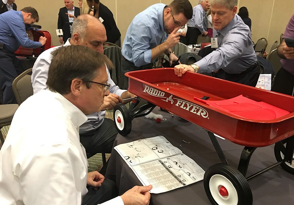 A group of people looking at a red wagon.
