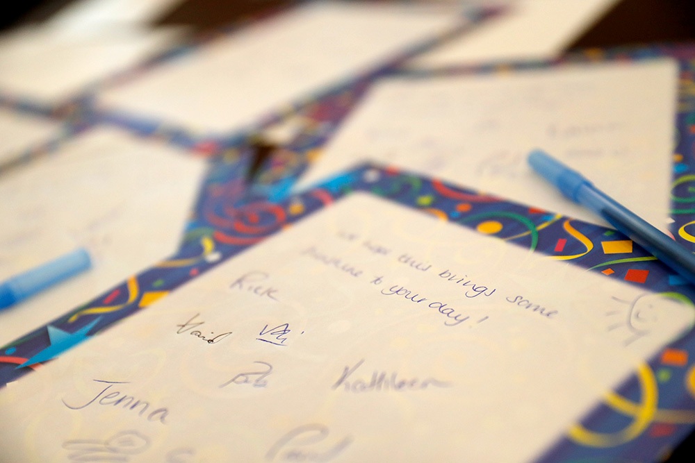 Handwritten notes on colorful stationary with blue pens scattered around.
