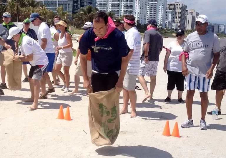 A group of people standing on an outdoors beach with orange cones.