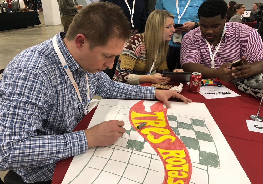 A group of people at a table making a sign.