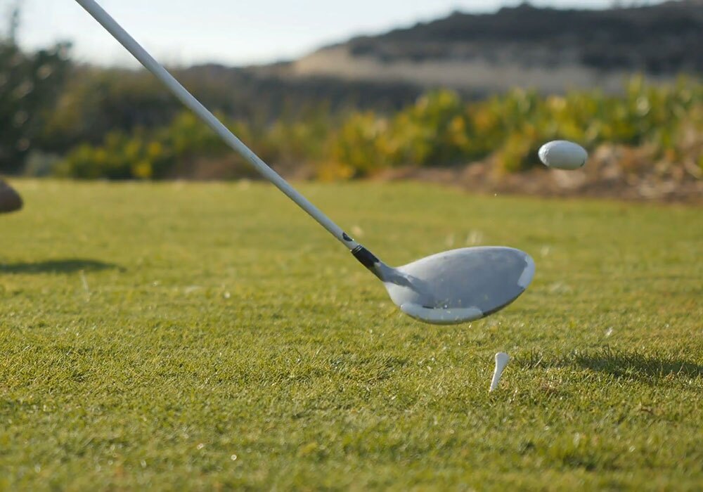 A person hitting a golf ball with a golf club.
