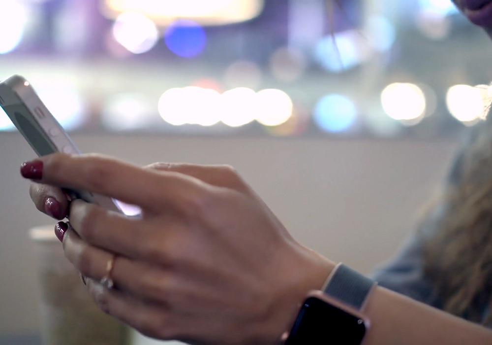 A woman is using a cell phone in a coffee shop.