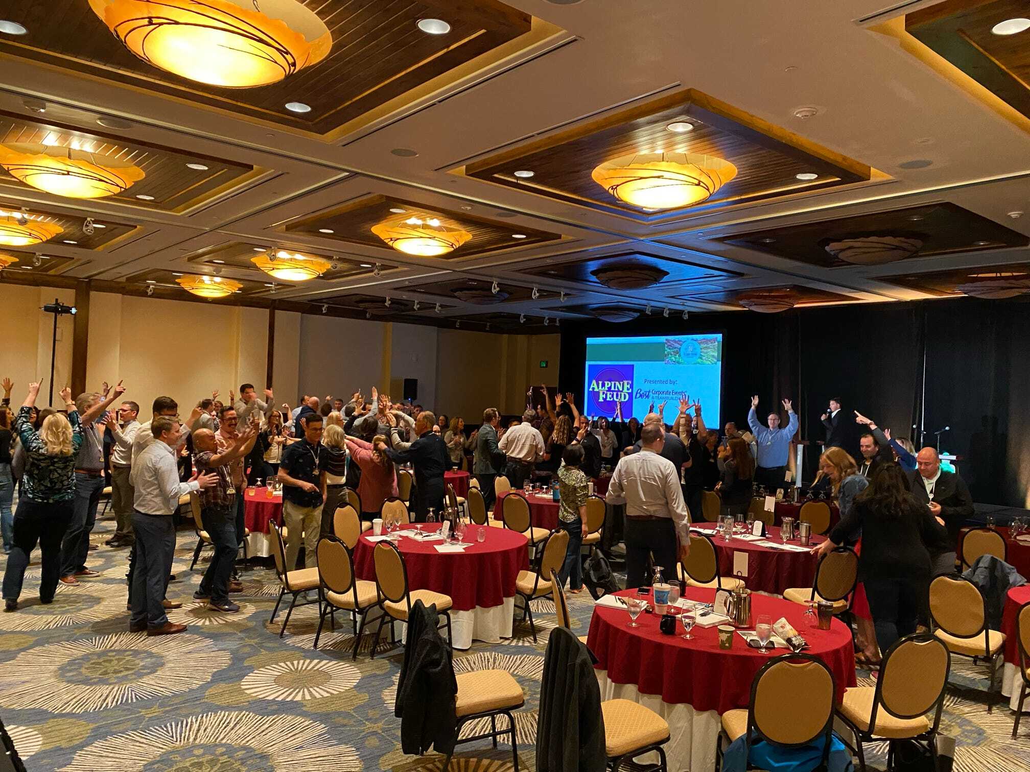 A group of people in a conference room raising their hands in the air.