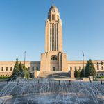 A fountain in front of a building with a clock tower.